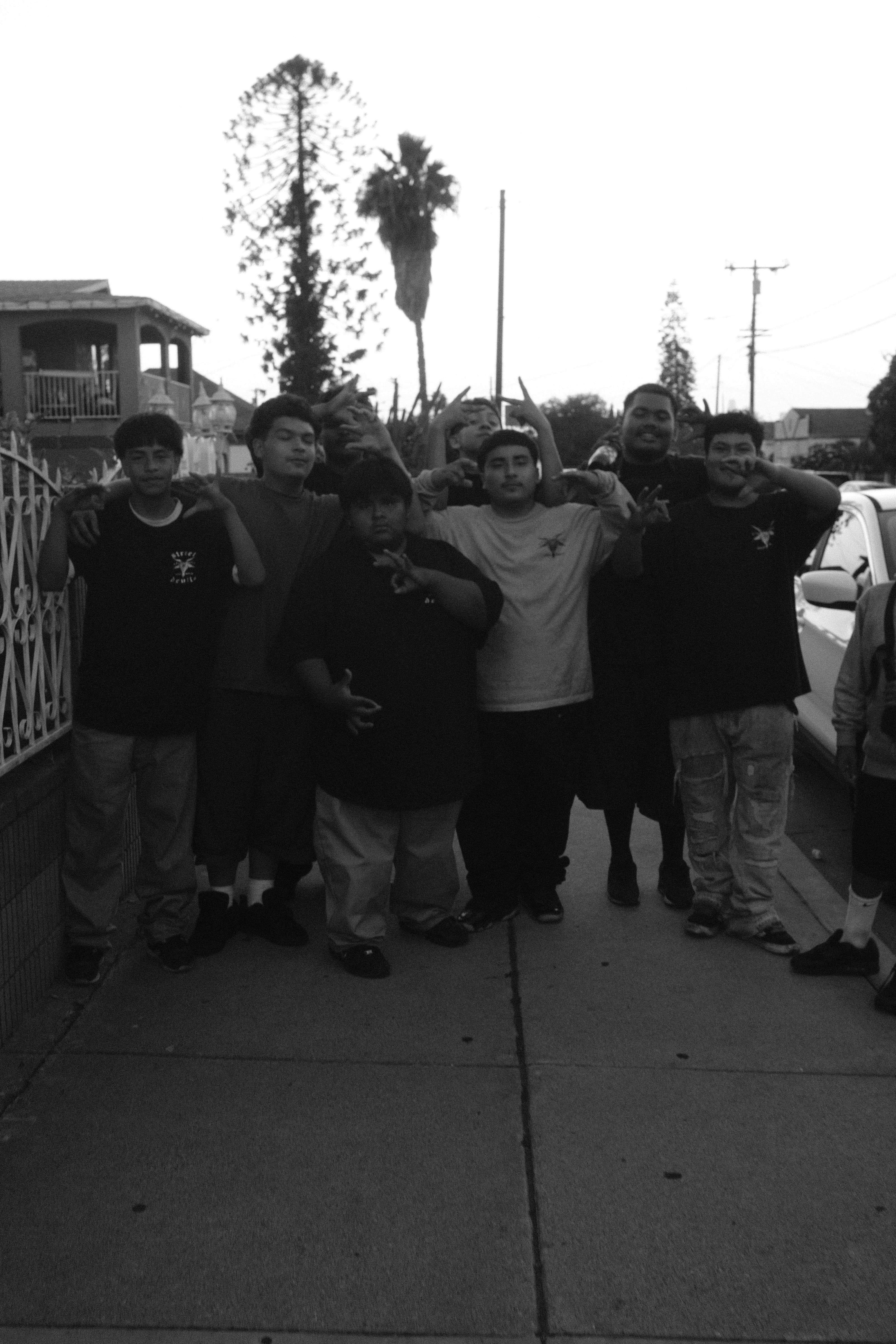 Young men standing together on a neighborhood sidewalk.